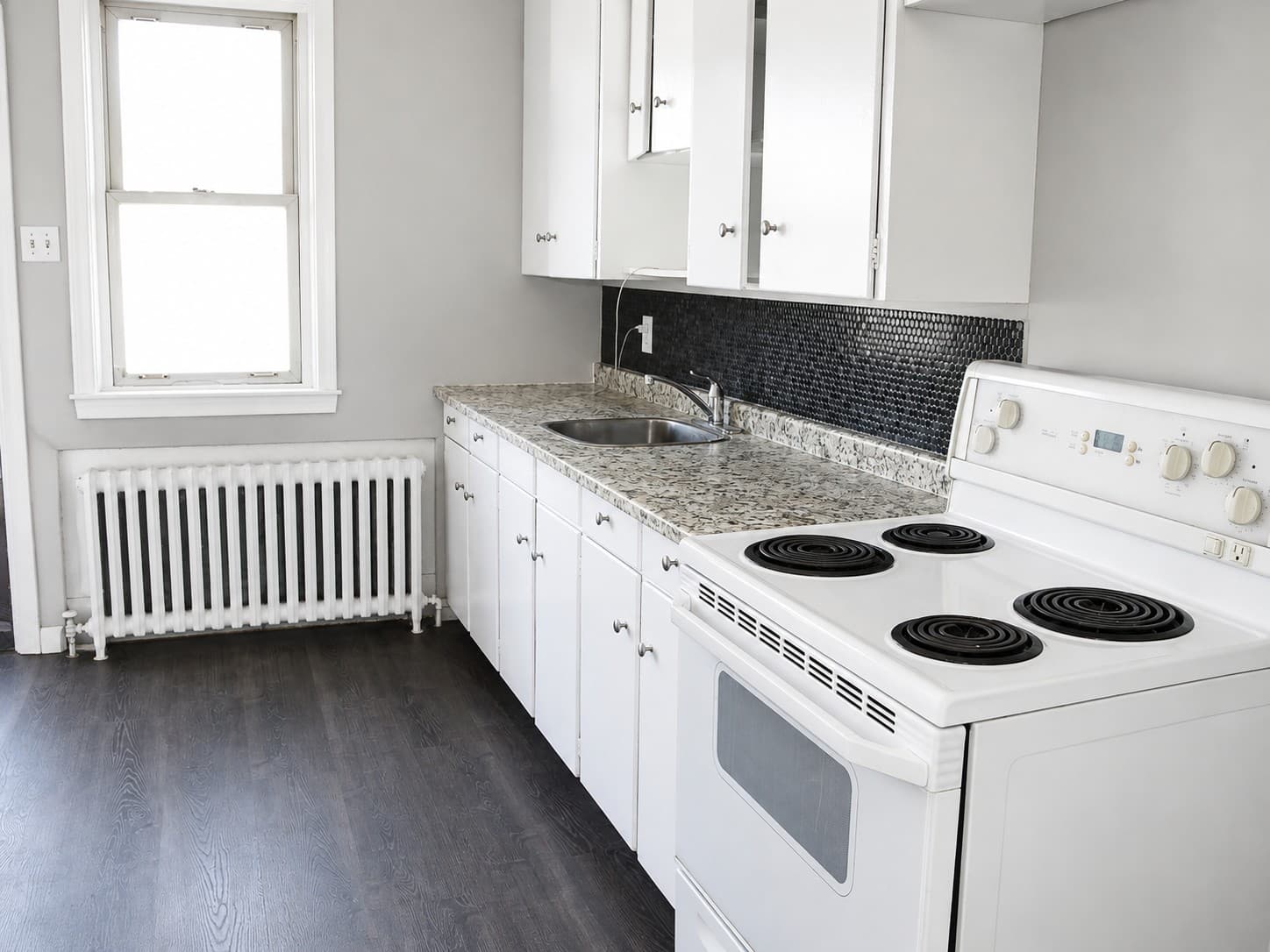 Clarence Apartments — kitchen with granite-look counter and tile backsplash